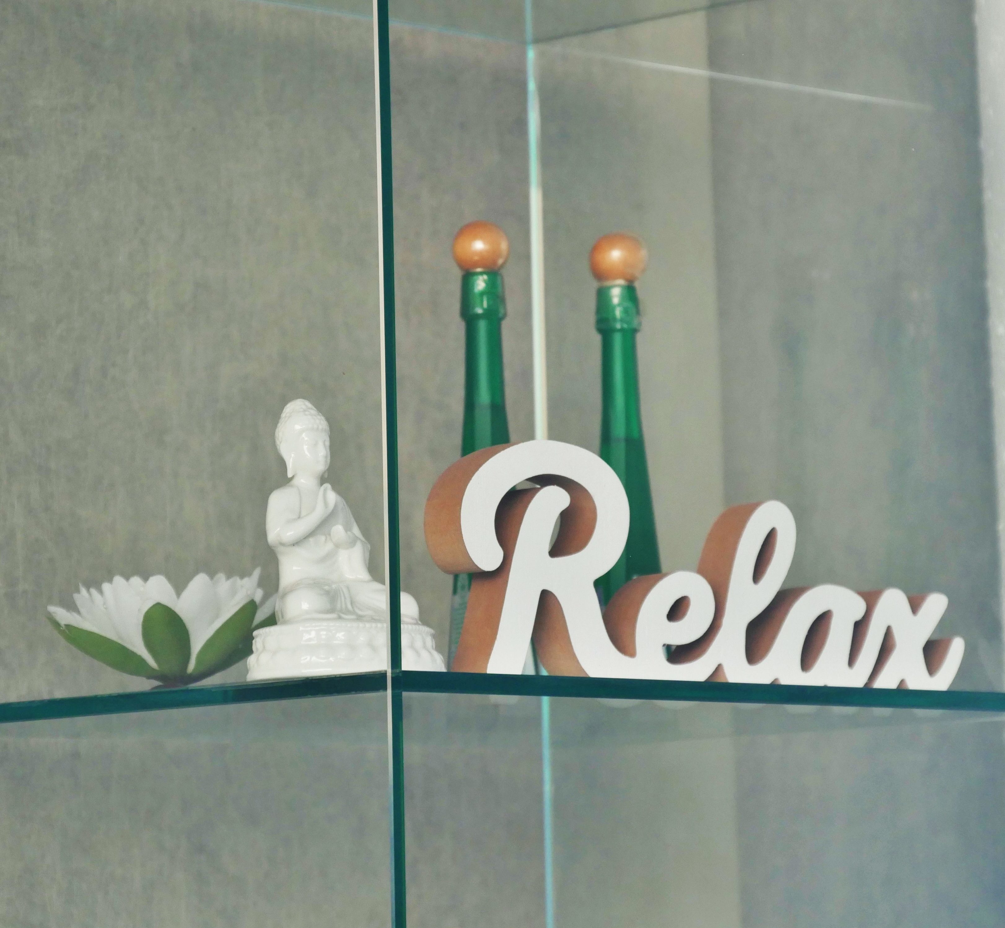 Eine Buddha-Figur, ein Schriftzug "Relax" aus Holz, eine Deko-Blume und zwei Fläschchen.