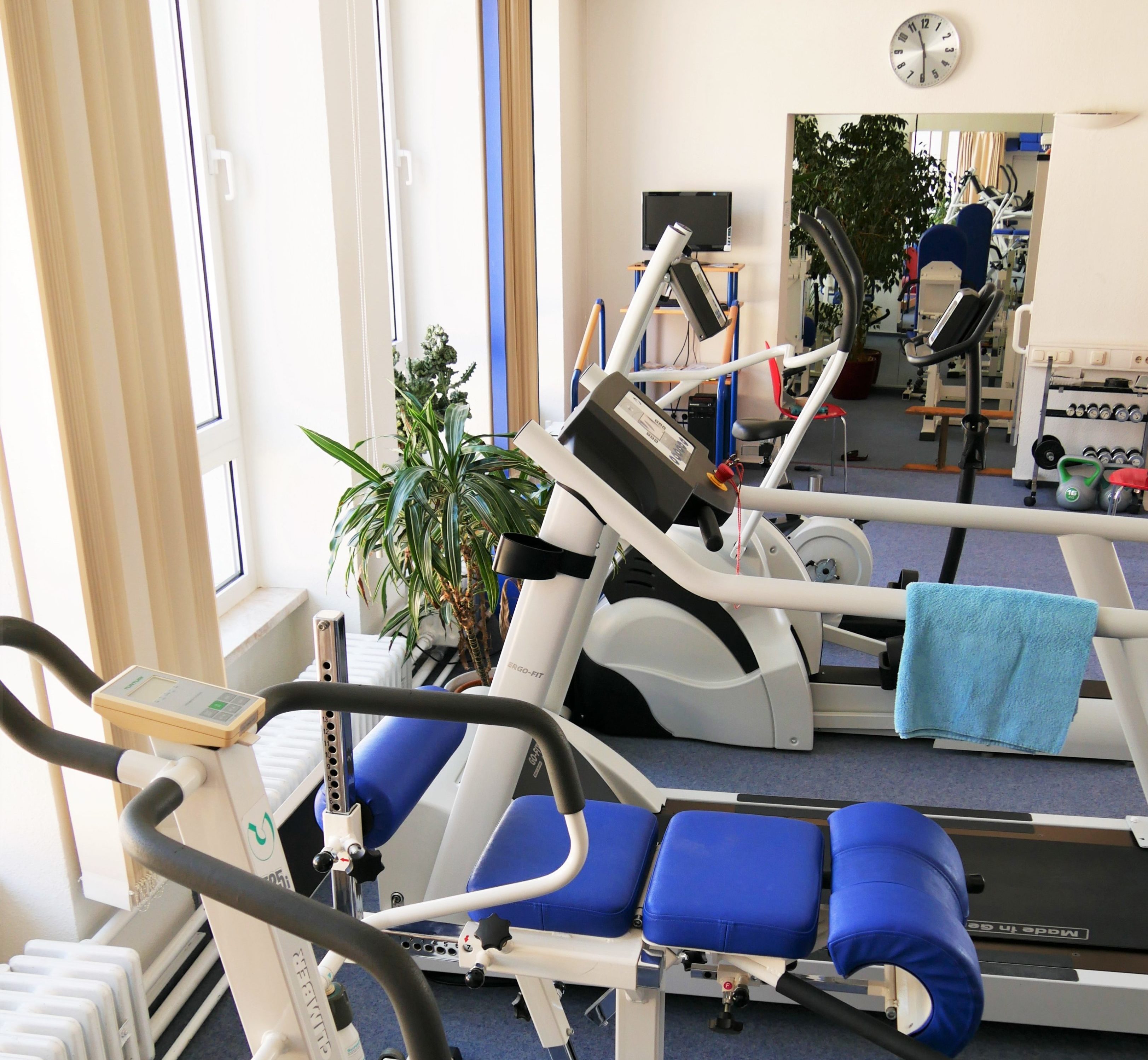 Anblick auf die Fitnessgeräte von oben: ein Ergometer, ein Cross-Trainer, ein Laufband und ein Stepper