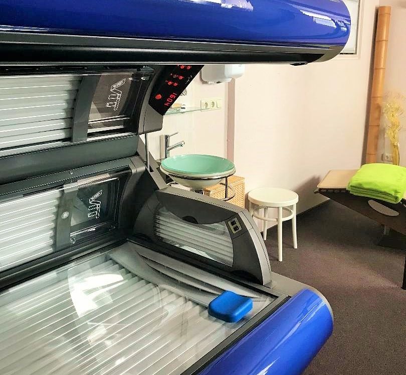 Blick in das Innere des Solariums, dahinter ein Waschbecken mit Spiegel und eine Liege